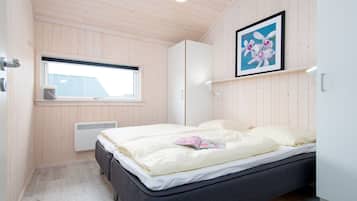 Ein Schlafzimmer mit einem Bett, einem Fenster, einem Heizkörper und einem gerahmten Bild an der Wand.
