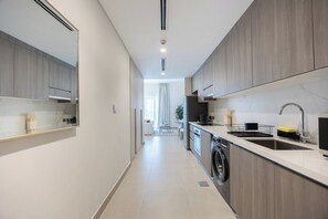Eine moderne Küche mit integriertem Waschtrockner, Spüle und einem Essbereich im Hintergrund.