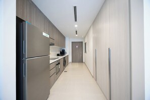 A modern kitchen with a built-in refrigerator, a microwave, and a coffee maker on the counter. - Bloomfields Studio in Fairways 1 -YGC (Abu Dhabi)