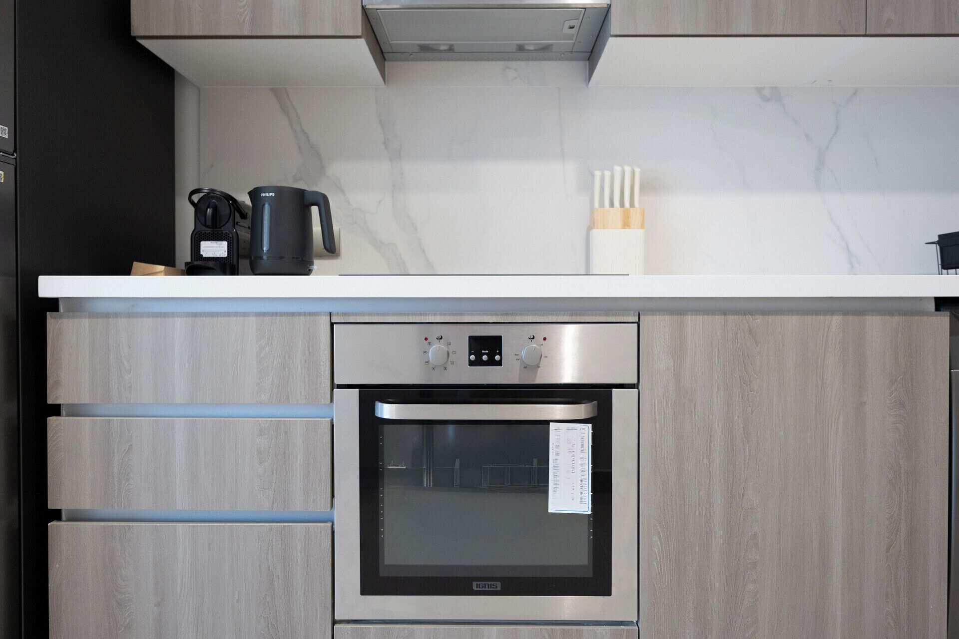 A kitchen with a built-in oven, a coffee maker, and a knife block on the countertop.