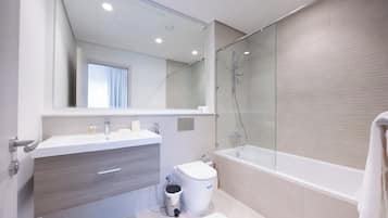 Un baño moderno con un espejo grande, una bañera y un inodoro.