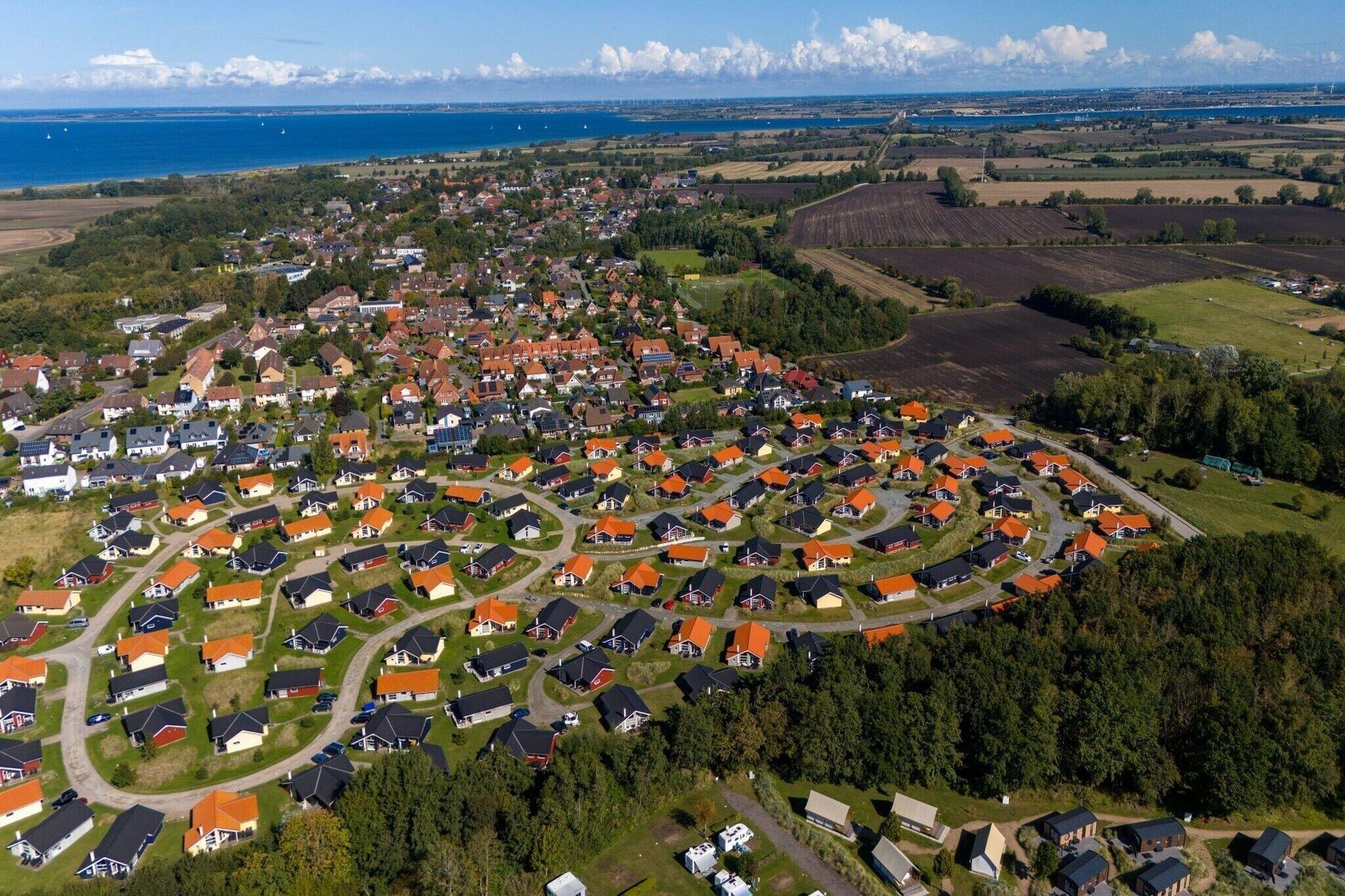 Vue aérienne d’un quartier résidentiel avec des maisons, des routes et une étendue d’eau en arrière-plan.