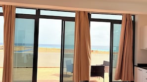 A room with large glass doors leading to a balcony overlooking a beach. - JoLi Penthouse — 60m² Rooftop Terrace, 360° View (Santa Maria)