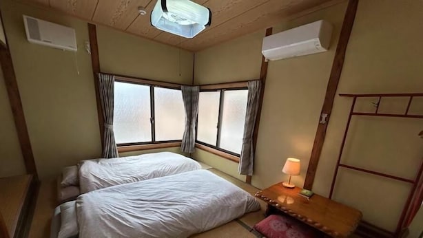 Une chambre avec deux lits, une table de chevet avec une lampe et une fenêtre avec des rideaux.