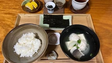 Una bandeja con un tazón de arroz, un tazón de sopa de pescado, un pequeño tazón de maíz y una taza de té.