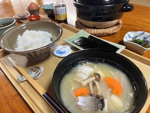 Un plateau repas contenant un bol de soupe, un bol de riz et une petite portion d’algues.