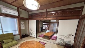 Une pièce de style japonais traditionnel, avec un sol recouvert de tatamis, une petite table en bois et une chaise verte.