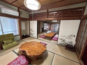 A traditional Japanese room with tatami flooring, a low wooden table, and a green chair.