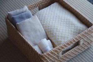 A woven basket containing folded towels and a bottle.