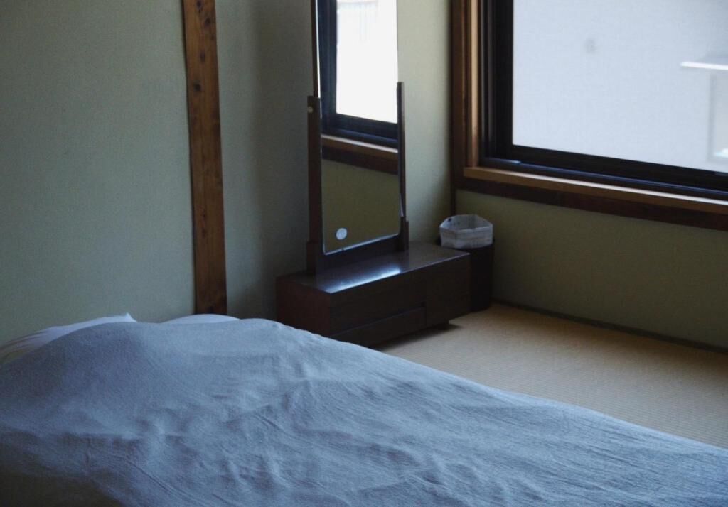 Une chambre à coucher avec un lit, une commode, un miroir et une fenêtre.