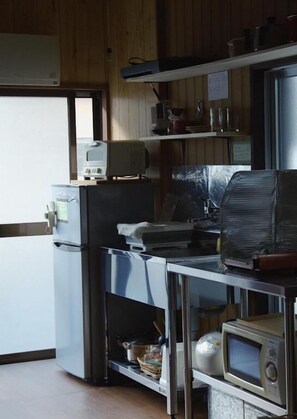 A kitchen with a refrigerator, microwave, and toaster on the counter.