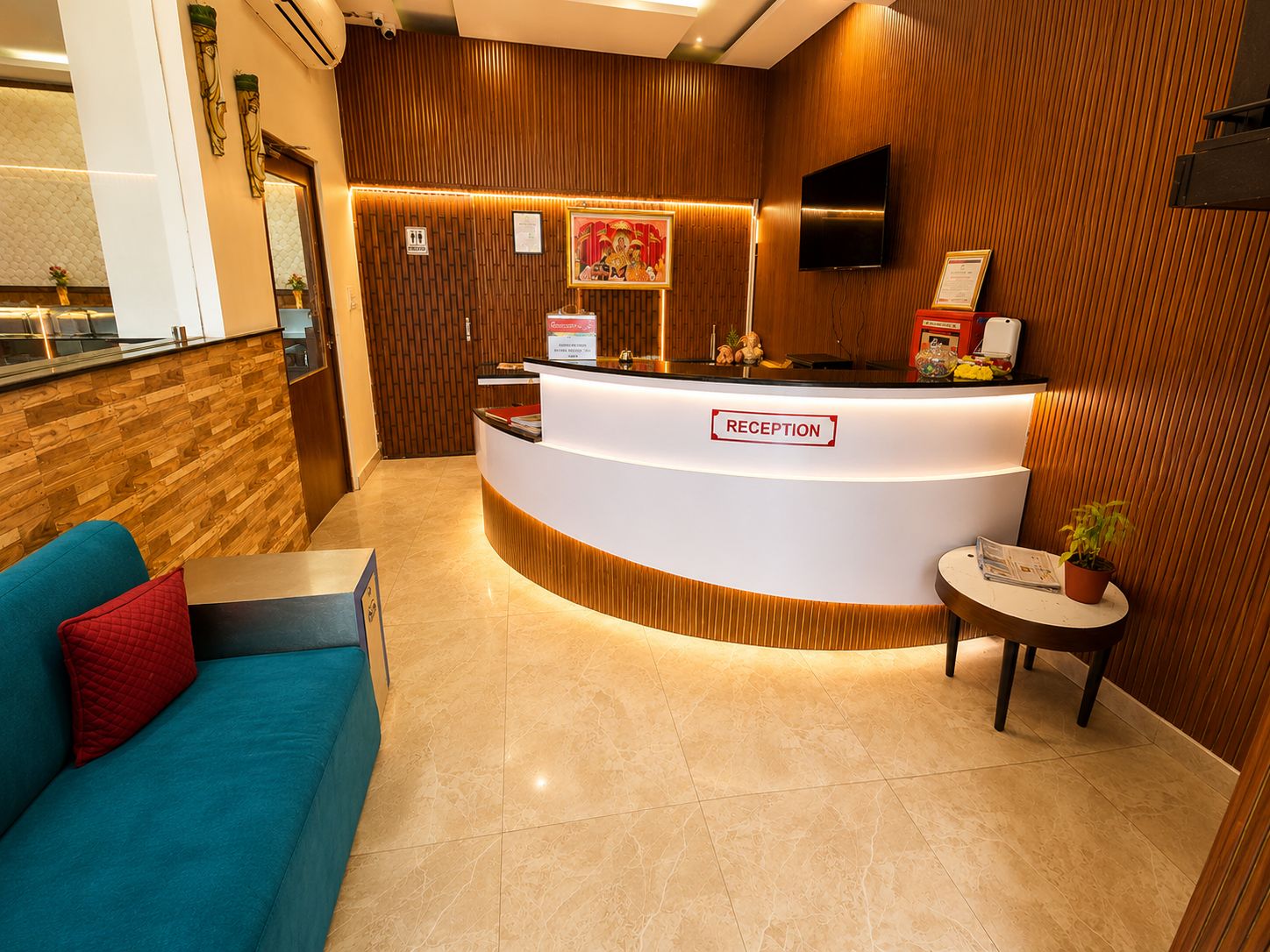 A reception area with a wooden reception desk, a sofa, and a small table with a plant.