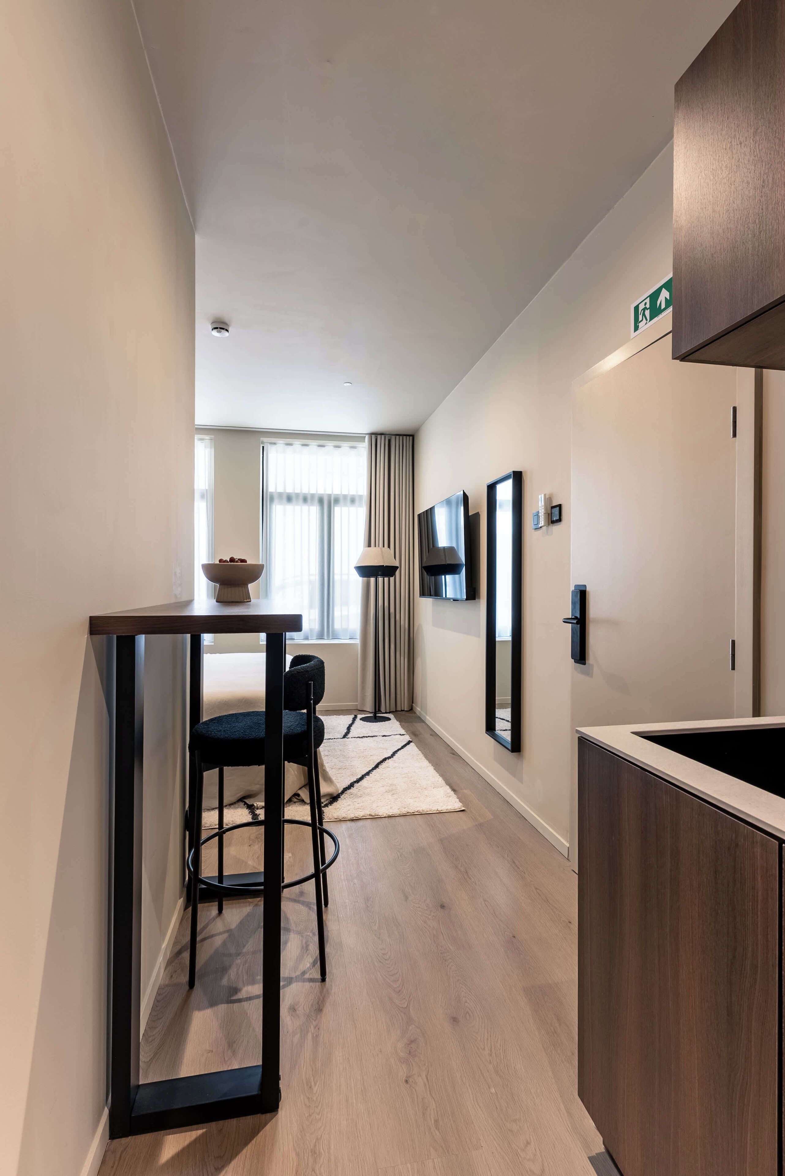 A hotel room with a dining area, a TV mounted on the wall, and a mirror.
