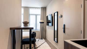 A hotel room with a dining area, a TV mounted on the wall, and a mirror.