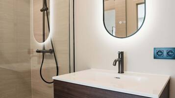 Deluxe studio | Badkamer | Een douche, een haardroger, handdoeken, zeep