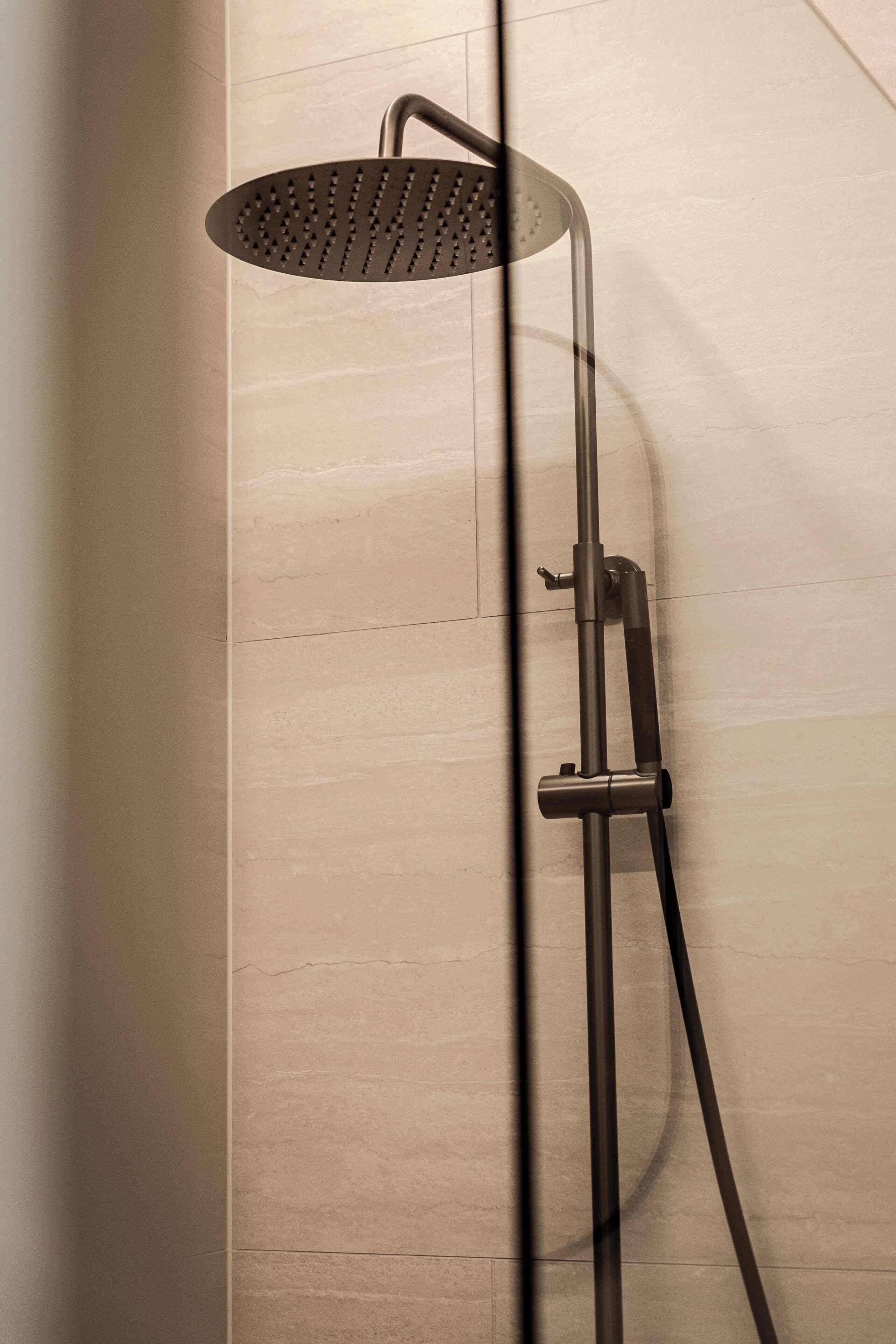 A modern shower with a handheld showerhead and a fixed wall-mounted showerhead.