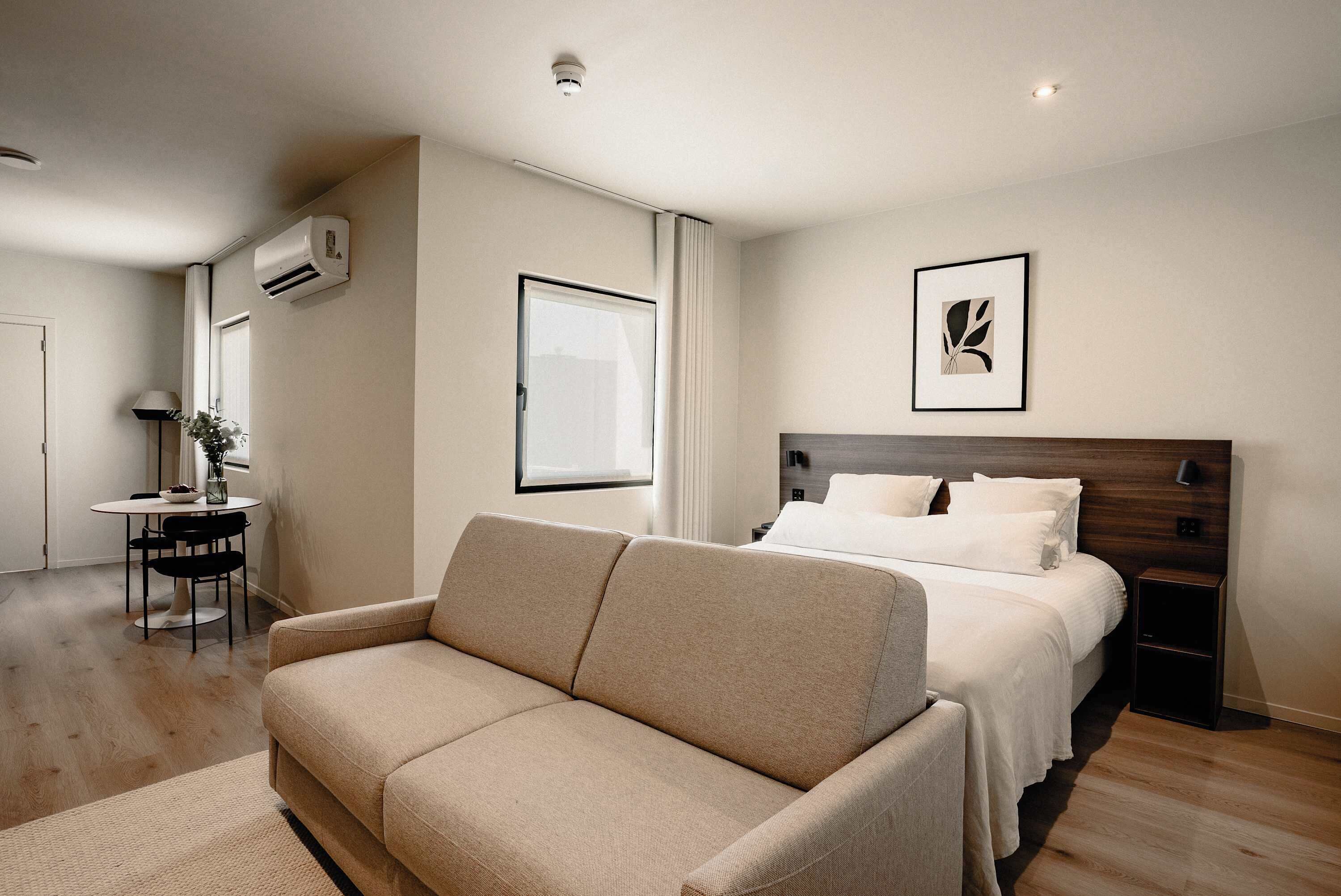 Habitación de hotel con cama, sofá, escritorio y silla, y ventana.