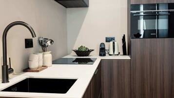 A modern kitchen with dark wood cabinetry, a stainless steel sink, and a built-in oven.