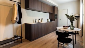 Una cocina moderna con armarios de madera oscura, encimera blanca y un comedor con mesa y sillas redondas.