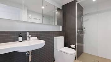 A modern bathroom with a white sink, a toilet, and a glass-enclosed shower area.
