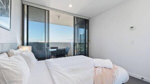 A hotel room with a large bed, a desk, and a sliding glass door leading to a balcony.