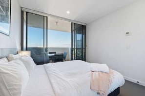 A hotel room with a large bed, a desk, and a sliding glass door leading to a balcony. - ML1306A Milton1306 ; 1 Bedroom 1 Bathroom (Brisbane)