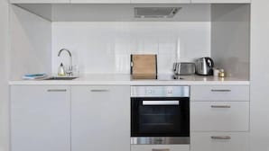 A modern kitchen with white cabinetry, a built-in oven, a sink with a faucet, and a toaster.