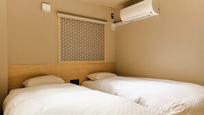 A hotel room with two beds, a wooden headboard, an air conditioning unit, and a window with a patterned blind. - Imakusa-so, Osaka: Tempozan - Ikisu - (大阪府大阪市港区築港3丁目10−11)
