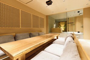 A modern interior with a wooden bench and cushioned seating, a decorative wall panel, and a large mirror reflecting a bathroom. - Imakusa-so, Osaka: Tempozan - Ikisu - (大阪府大阪市港区築港3丁目10−11)