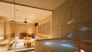 A modern spa room with a glass-enclosed seating area, a wooden table, and a large hot tub. - Imakusa-so, Osaka: Tempozan - Ikisu - (大阪府大阪市港区築港3丁目10−11)