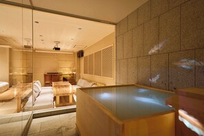 Ein moderner Spa-Bereich mit einer verglasten Sitzgelegenheit, einem Holztisch und einer großzügigen Whirlwanne.