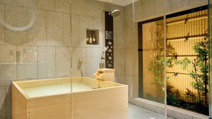 A modern bathroom with a wooden bathtub, a glass shower enclosure, and a view of a bamboo garden. - Imakusa-so, Osaka: Tempozan - Ikisu - (大阪府大阪市港区築港3丁目10−11)