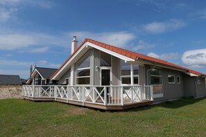Ein zweistöckiges Haus mit überdachter Veranda und einem eingezäunten Deck.