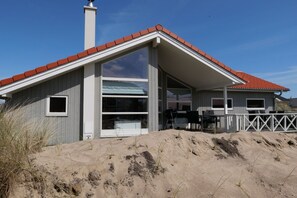 A two-story building with a red-tiled roof, large windows, and a covered outdoor seating area. - Luxuriöses Küstenretreat für 10 Personen (Großenbrode)