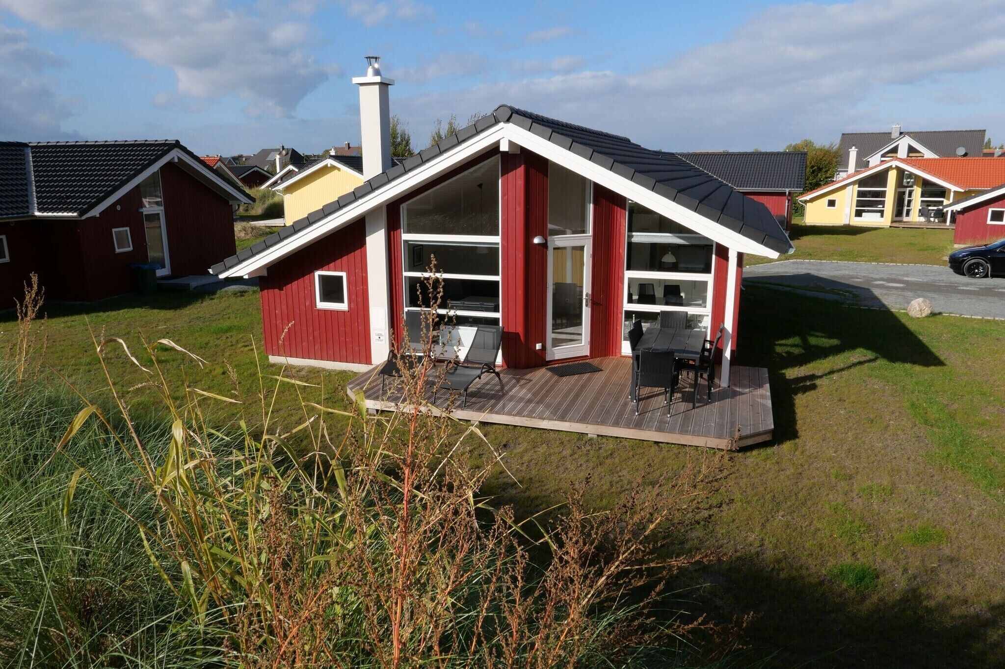 Une petite cabane rouge avec une terrasse couverte et une cheminée.
