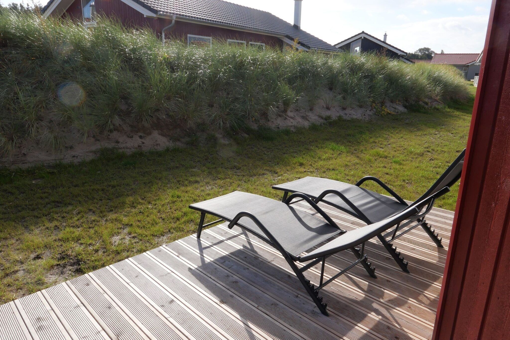 Eine Terrasse mit zwei Stühlen und einem Tisch, umgeben von einer Rasenfläche und einer Holzterrasse.