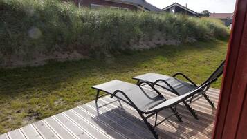Eine Terrasse mit zwei Stühlen und einem Tisch, umgeben von einer Rasenfläche und einer Holzterrasse.