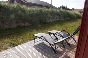 Eine Terrasse mit zwei Stühlen und einem Tisch, umgeben von einer Rasenfläche und einer Holzterrasse.