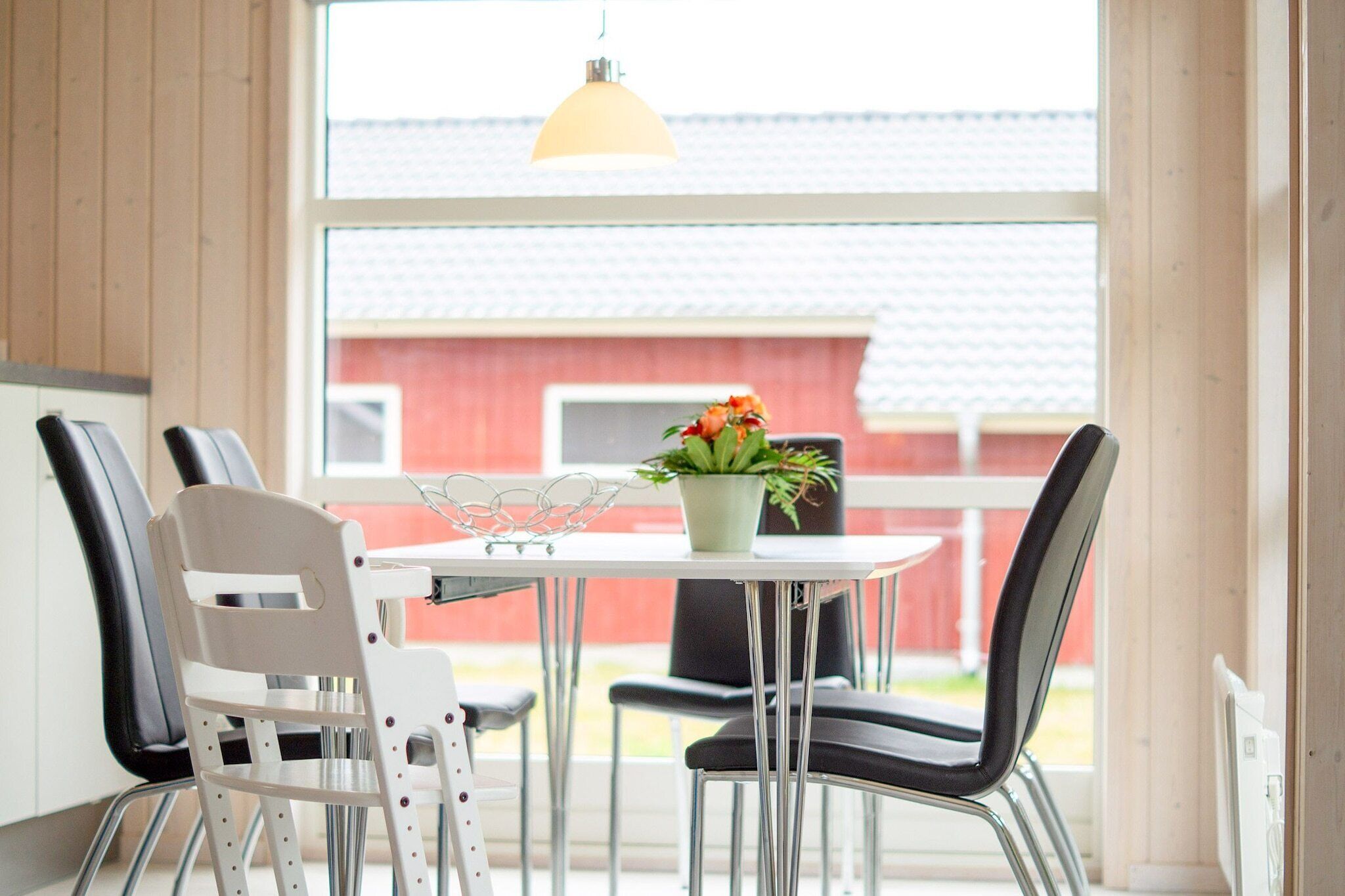 A dining area with a table, chairs, and a hanging light fixture.
