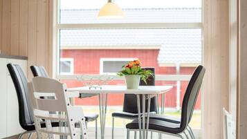 A dining area with a table, chairs, and a hanging light fixture.