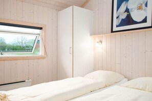 Ein Schlafzimmer mit einem Einzelbett, einem Kleiderschrank, einem Fenster und einer Wandleuchte.