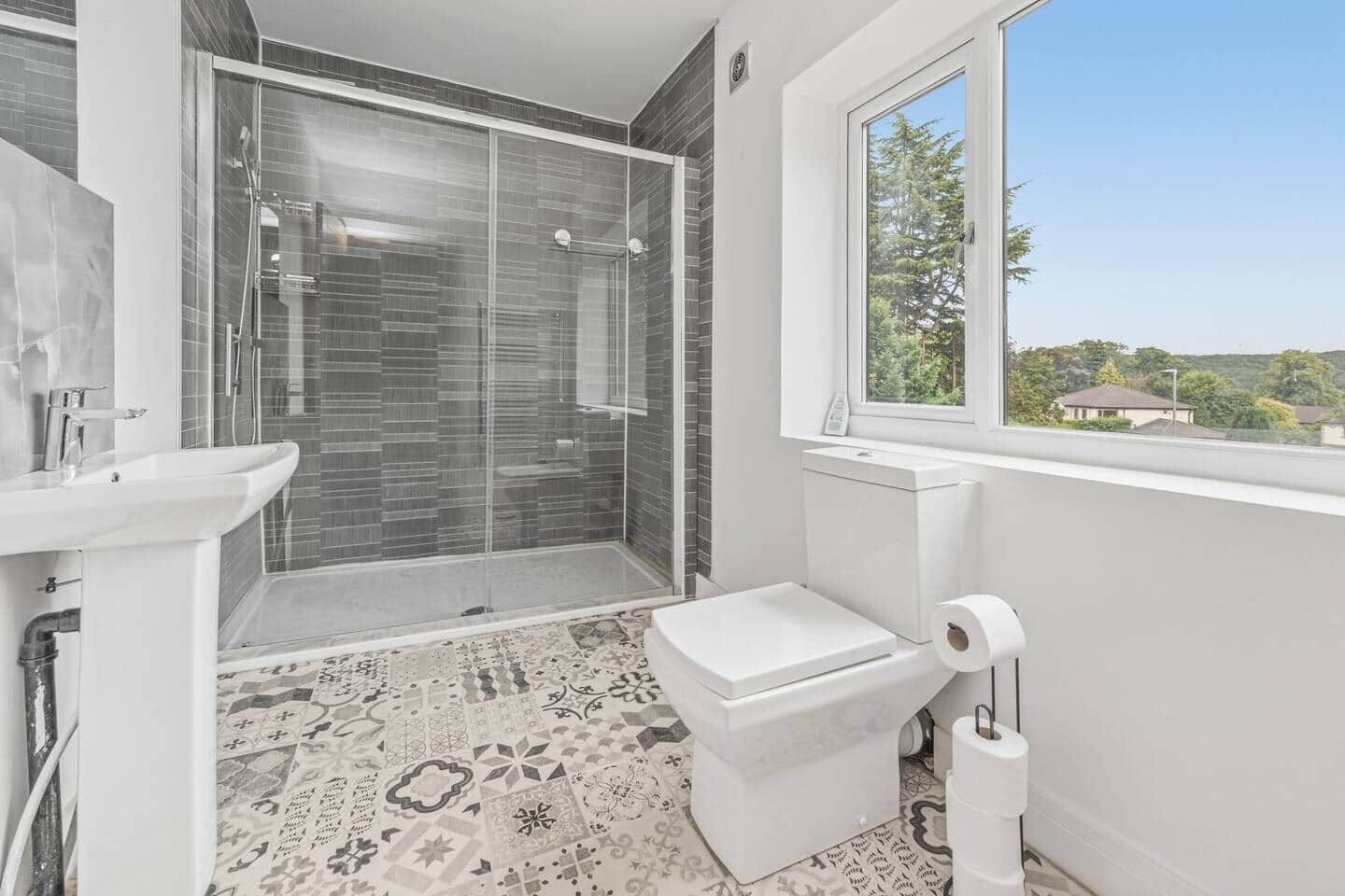 Un baño moderno con ducha envuelta en vidrio, inodoro y lavamanos.