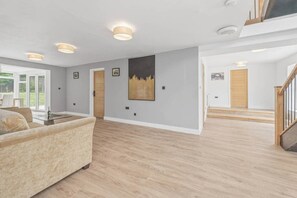 Un vaste espace de vie comprenant un canapé, une table à manger et un escalier menant à l’étage supérieur.