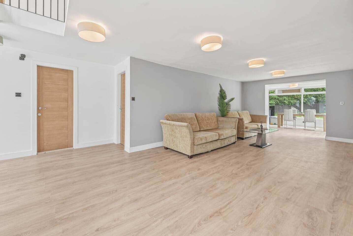 A spacious living room with a light-colored sofa, a coffee table, and recessed ceiling lights.