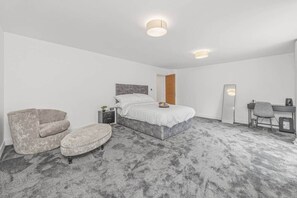 Un dormitorio con cama, una silla, un escritorio y un espejo.