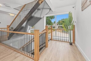 A staircase with a wooden handrail and metal balusters, leading to an outdoor area with a view of greenery and a clear sky. - Victoria Suite - Huddersfield Suite 2 (Huddersfield)