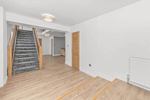 Ein modernes Interieur mit Treppe, Holzböden und weißen Wänden.
