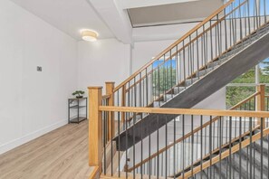 Un escalier moderne avec des rampes en bois et des balustrades en métal, menant à l’étage sup érieur.