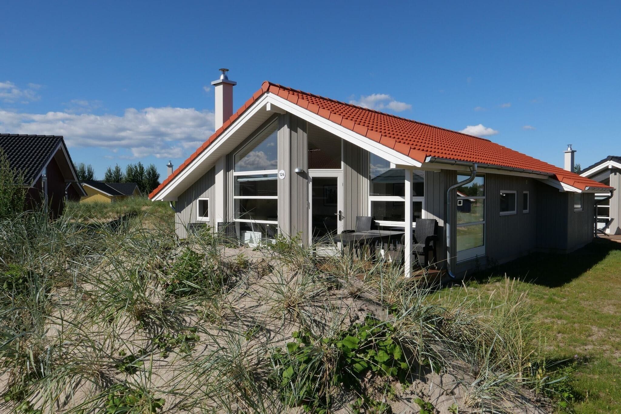 Ett modernt hus med ett rött tegeltak, stora fönster och nummer 126 på dörren.