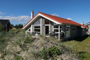 A modern house with a red-tiled roof, large windows, and a number 126 on the door. - Charmantes Cottage für 8 Personen mit Sauna (Großenbrode)
